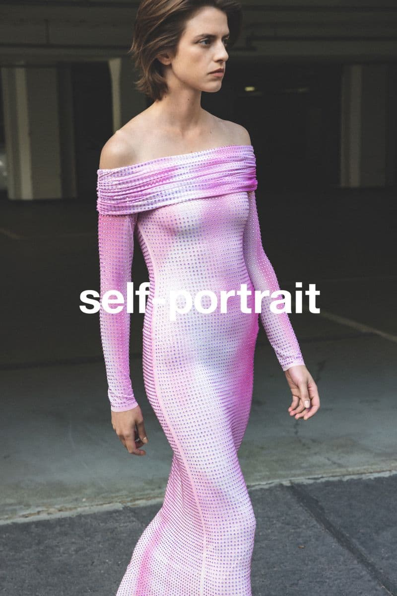 Woman in a stylish off-the-shoulder pink dress posing in an urban setting with concrete walls, showcasing fashion and modern style.