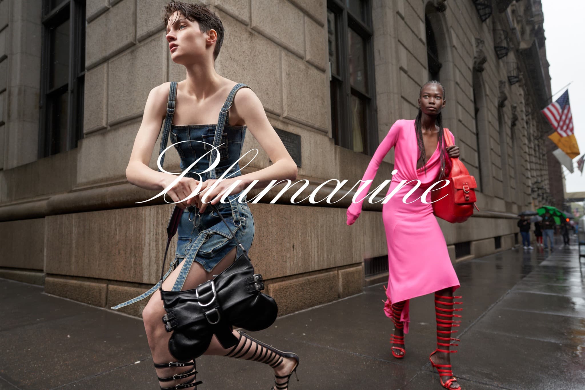 Two fashion models pose on a city street wearing designs from Blumarine. One is in denim and the other is in hot pink.