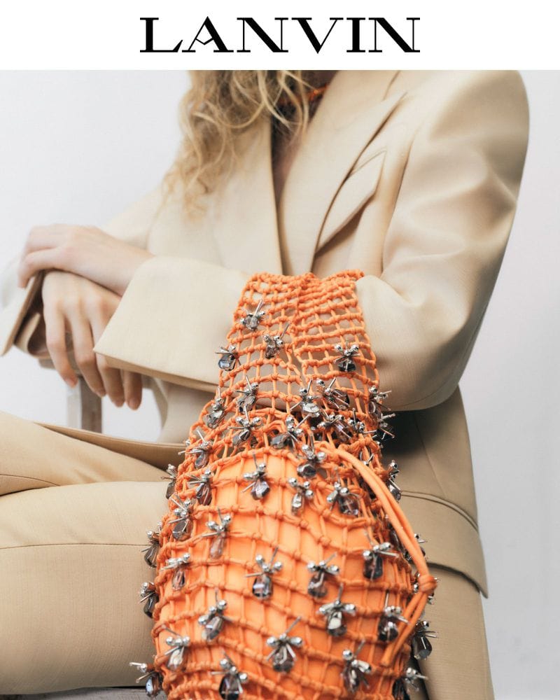 Fashionable beige women's suit jacket paired with an orange net purse adorned with silver embellishments, showcasing luxury and style.