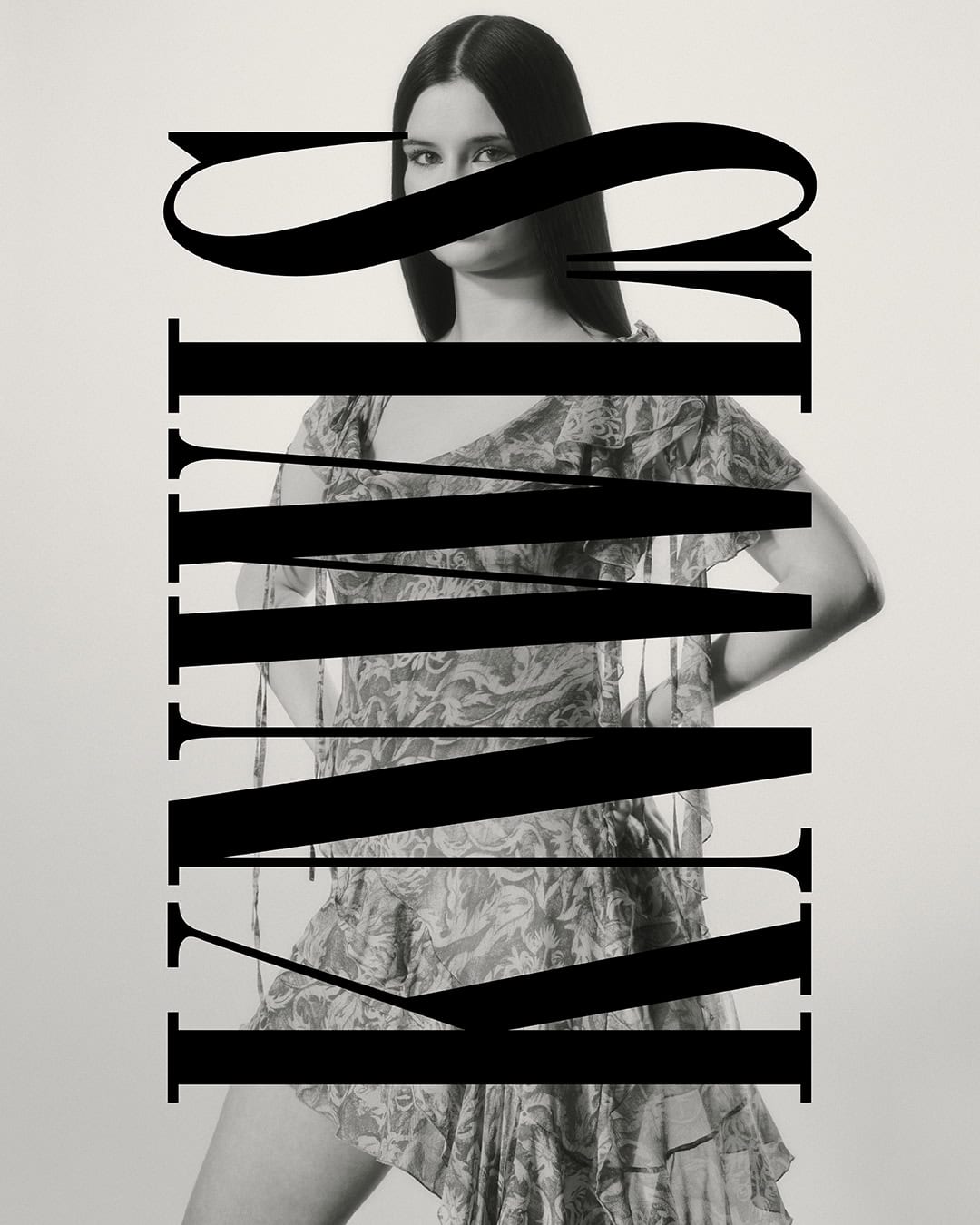 Monochromatic fashion shot of a slender adult woman wearing a floral mini dress, large typography overlay in studio setting.