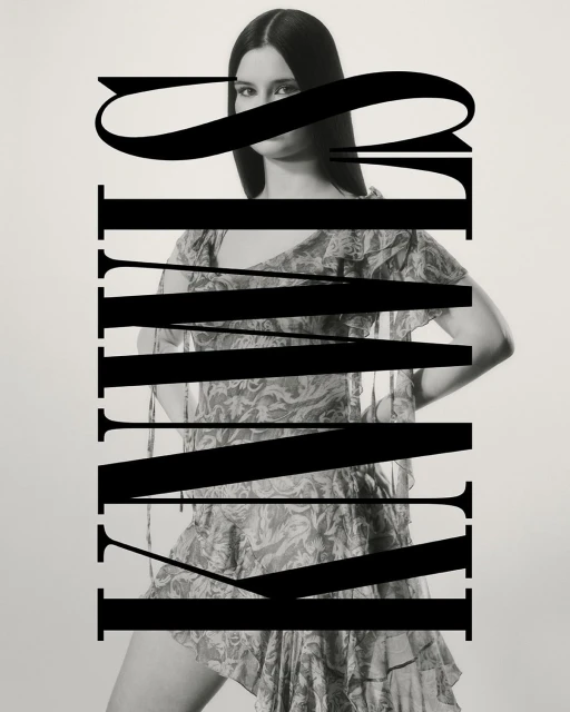 Monochromatic fashion shot of a slender adult woman wearing a floral mini dress, large typography overlay in studio setting.