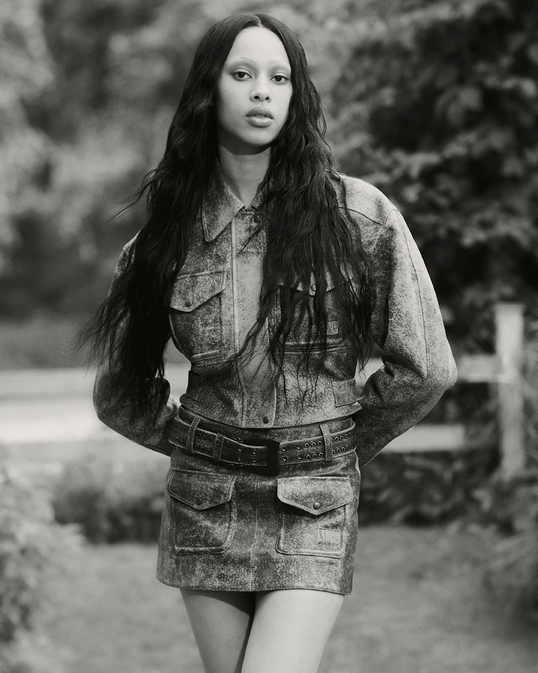 Model wearing a textured denim jacket and matching skirt in an outdoor setting for KNWLS Proxy 2.0 campaign