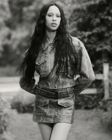 Model wearing a textured denim jacket and matching skirt in an outdoor setting for KNWLS Proxy 2.0 campaign