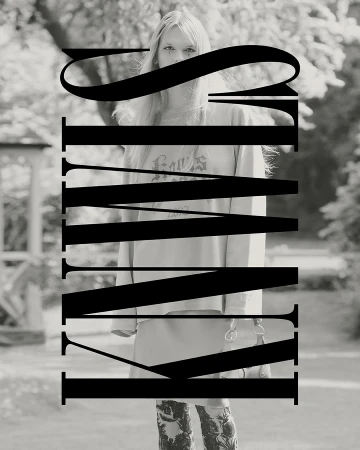 Black and white portrait of a woman with long blonde hair, a sweatshirt and patterned pants, standing outside with trees in the background.