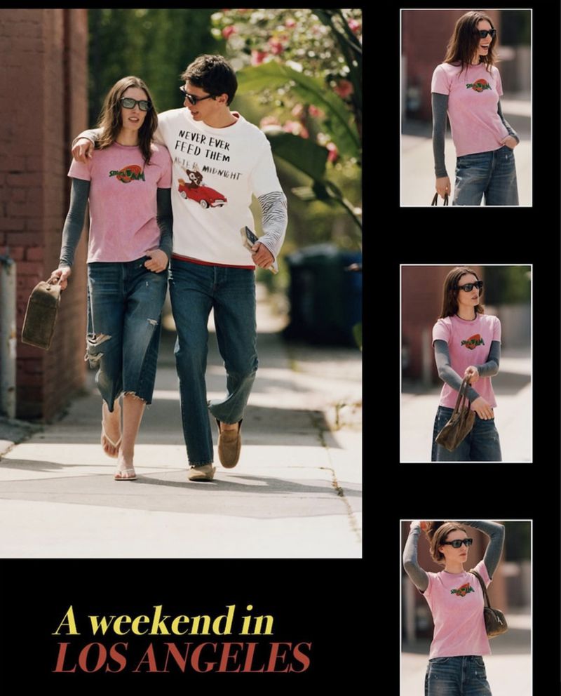 A stylish couple strolls down a sunny city street, wearing casual outfits and sunglasses, next to the brick wall and lush greenery.