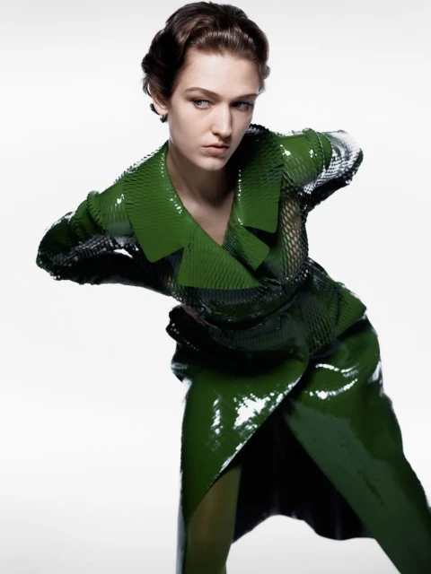 Fashion portrait of a woman in a green shiny outfit, posed against a white backdrop, showcasing a modern and stylish look.