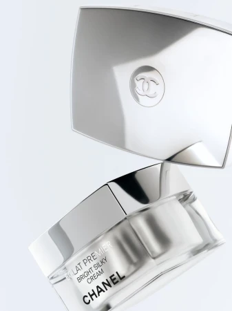 Chanel skincare product is displayed with a mirrored cosmetic compact on a clean, white background in a beauty still life shot.