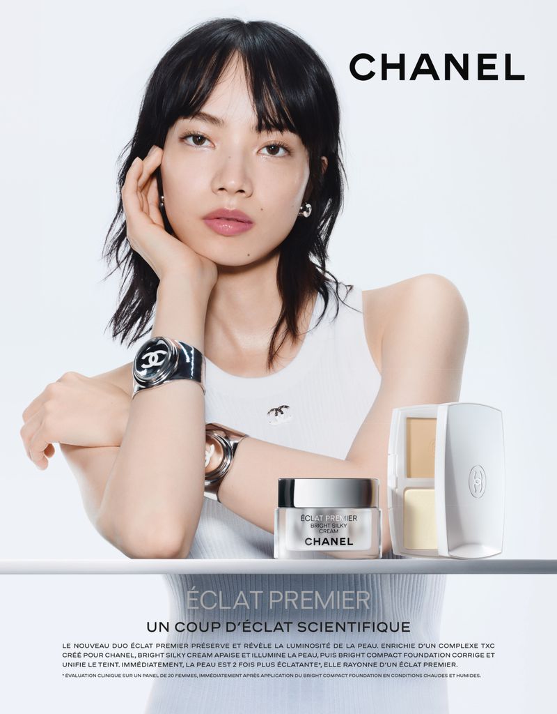 Cosmetics ad featuring a woman with black hair wearing a white top and Chanel watches, alongside Chanel Éclat Premier skincare products.