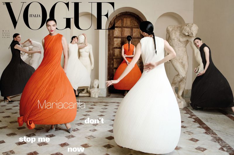 Vogue Italia cover featuring a woman in an orange dress, surrounded by women in black and white dresses and classical sculptures.