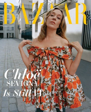 Chloe Sevigny in an off-the-shoulder floral dress standing on an outdoor street for Harper's Bazaar May 2026