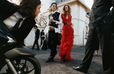 Group of diverse models in stylish clothing standing outside a light building on an urban street.