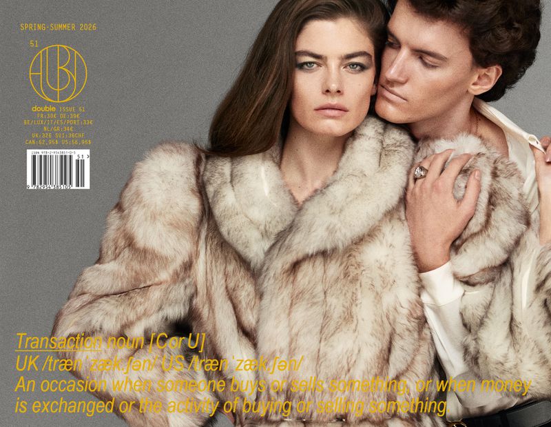 Magazine cover featuring two people wearing fur coats in a photo studio with muted colors and modern typography.