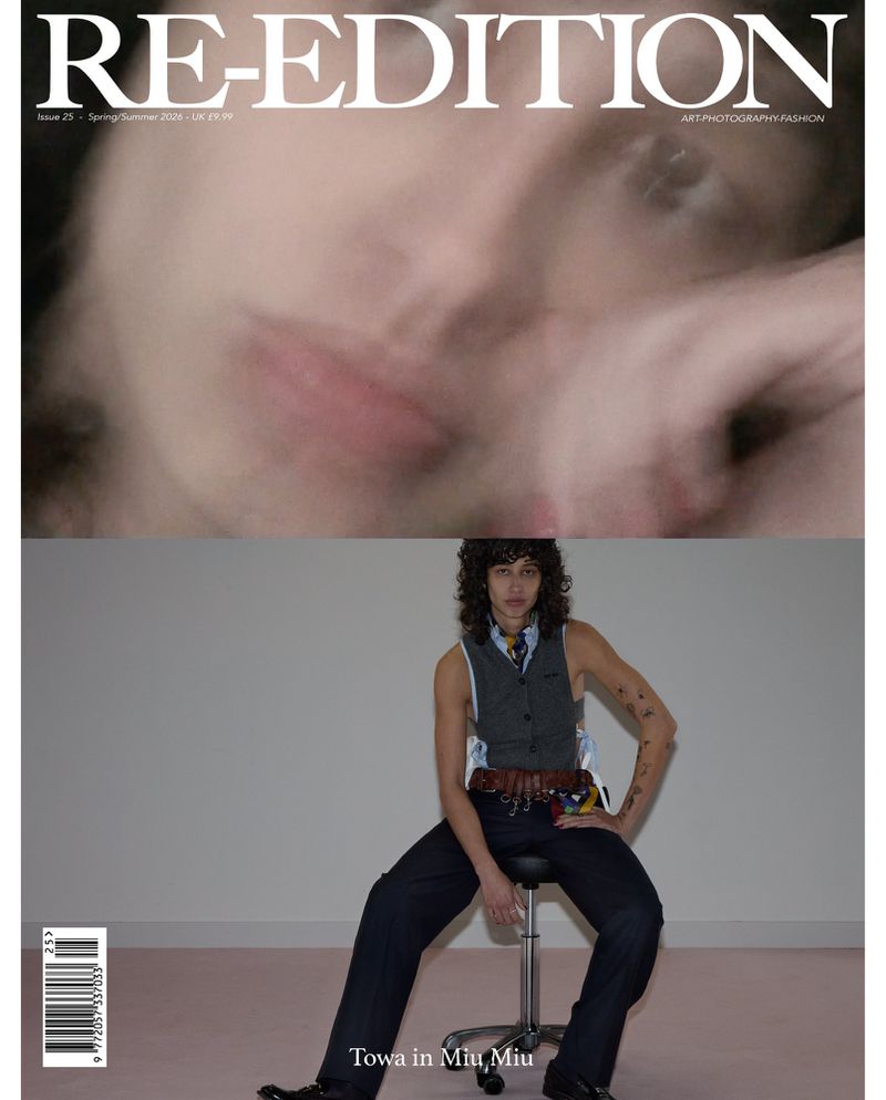 Magazine cover featuring a blurry face at the top and a person in a vest and trousers seated on a stool below.