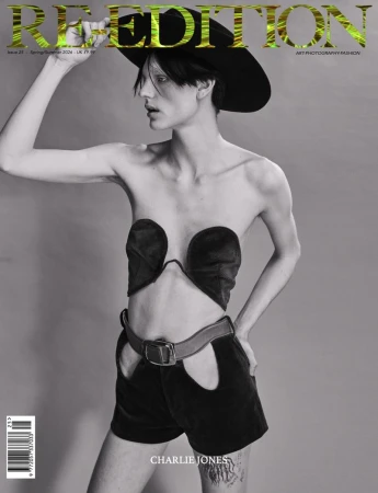 Fashion magazine cover featuring a model in black vintage-style clothing and a wide-brimmed hat against a gray backdrop.