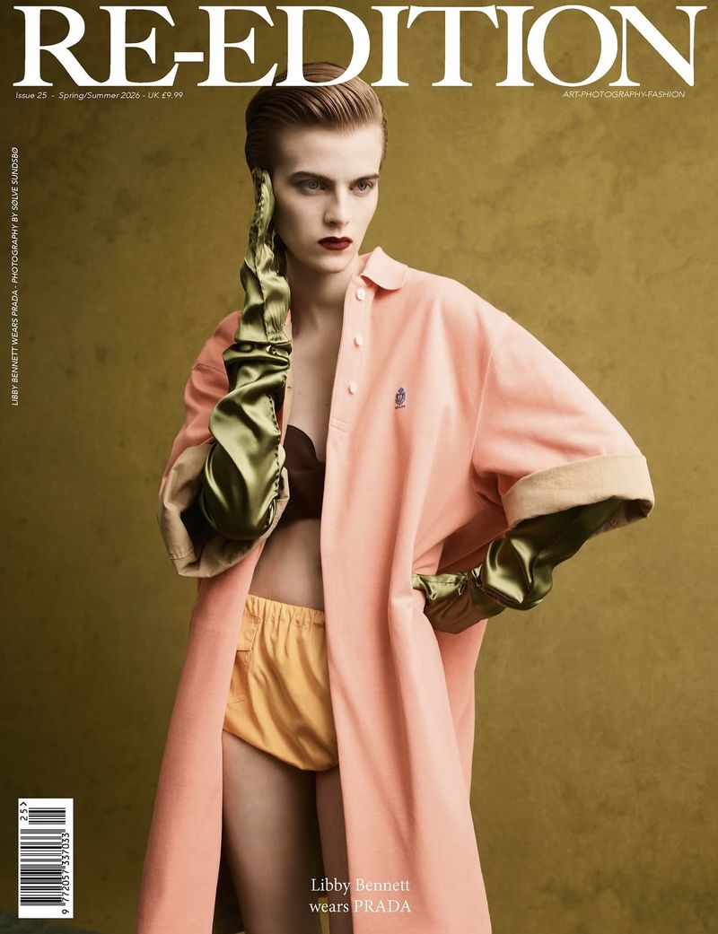 Magazine cover featuring a fashion model wearing a pink coat, brown bra, and yellow shorts, with glossy green gloves, against a warm-toned background.