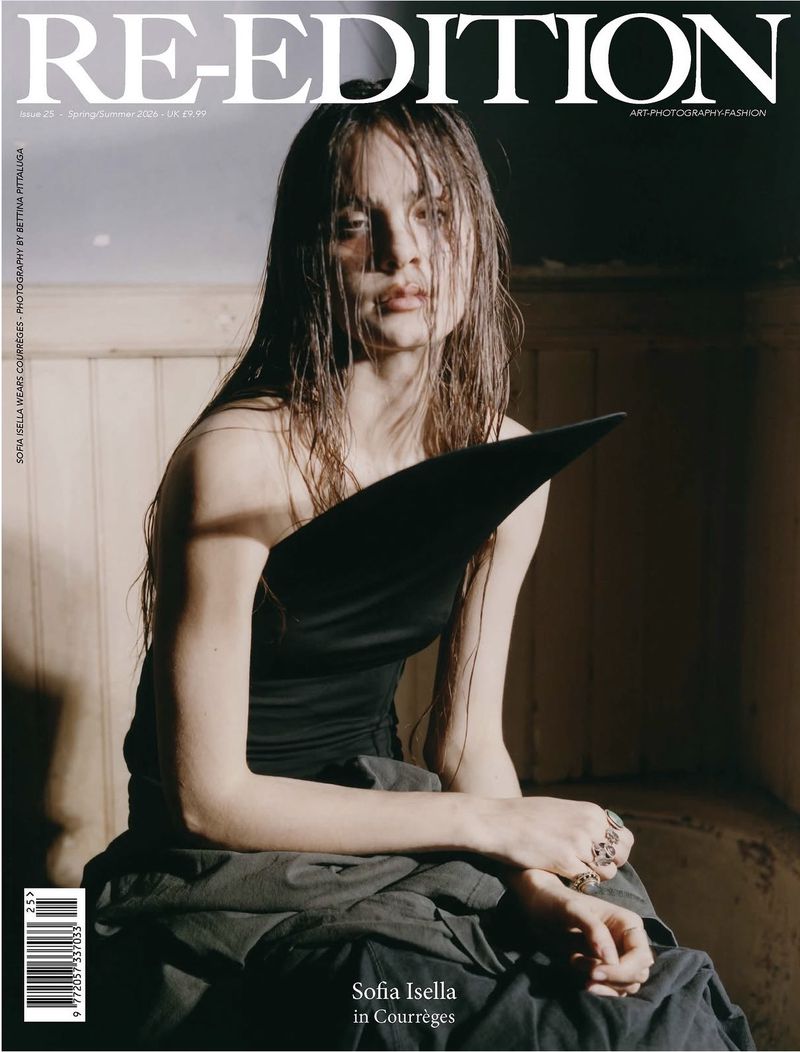 Magazine cover featuring a woman with wet hair wearing a black top and draped grey fabric, posing in an indoor setting.
