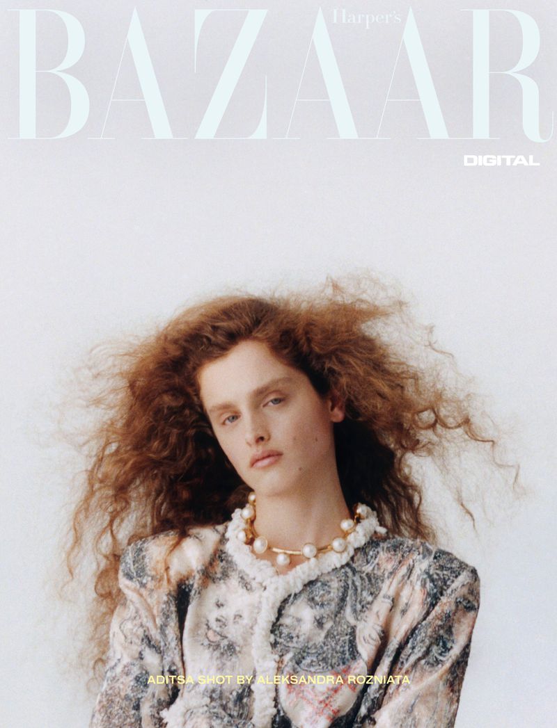 Fashion editorial image featuring a red-haired woman with a pearl necklace and patterned jacket against a clean white backdrop for Bazaar.