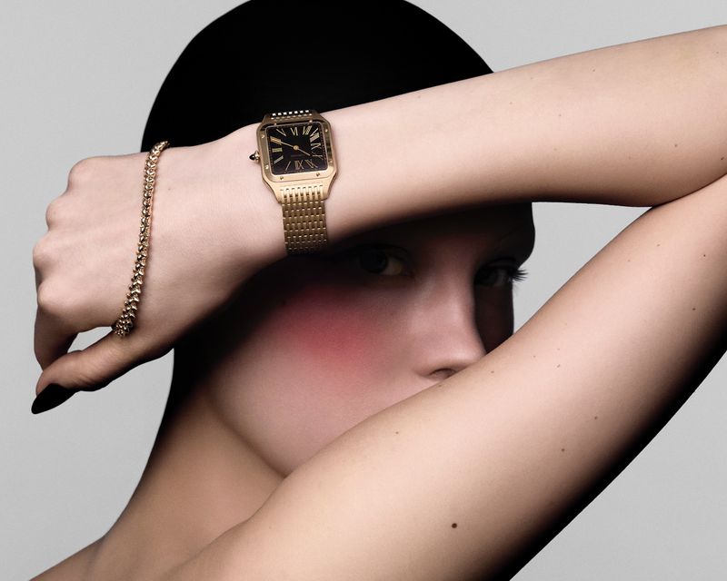 Close-up shot of a woman wearing a gold watch and bracelet against a neutral background, highlighting beauty and fashion accessories.