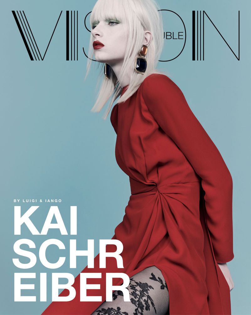 Magazine cover featuring a blond fashion model in a long-sleeved red dress and lace tights against a light blue background.