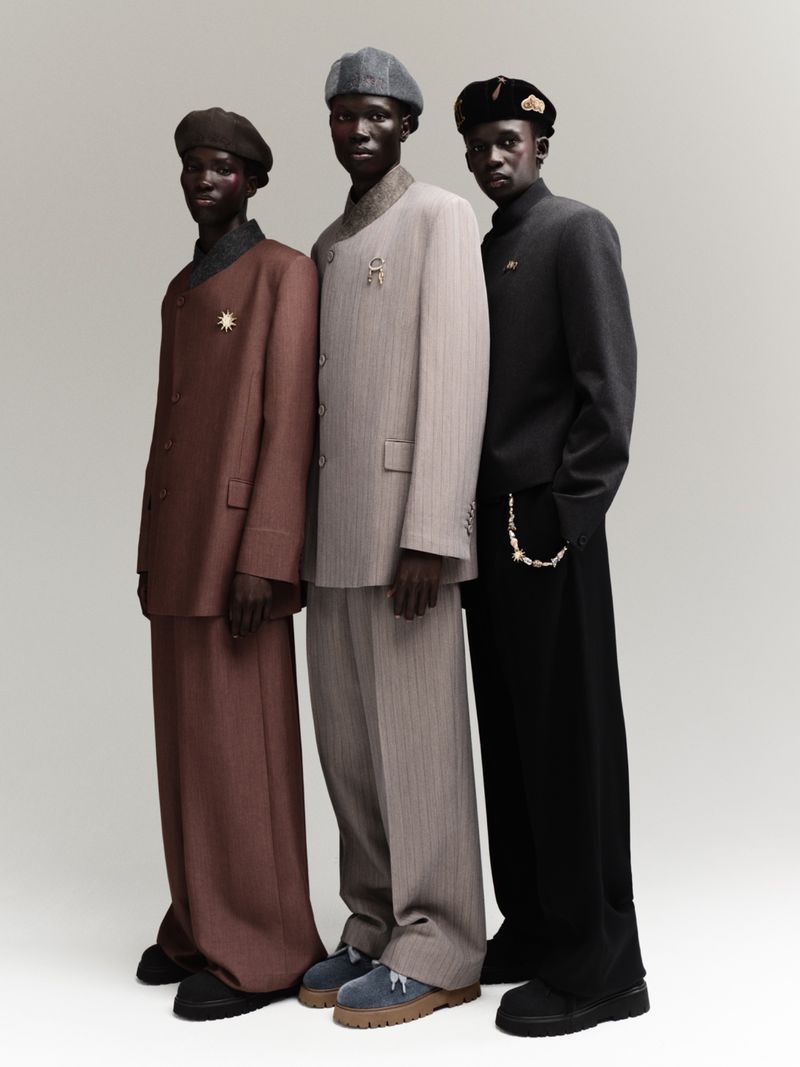 Three Black men in stylish suits and berets pose in a studio, showcasing high fashion with classic tailoring and elegant accessories.