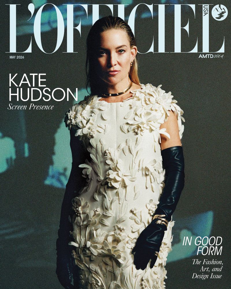 L'Officiel magazine cover featuring Kate Hudson in a white floral dress and black gloves, set against a blurred, shadowy background.