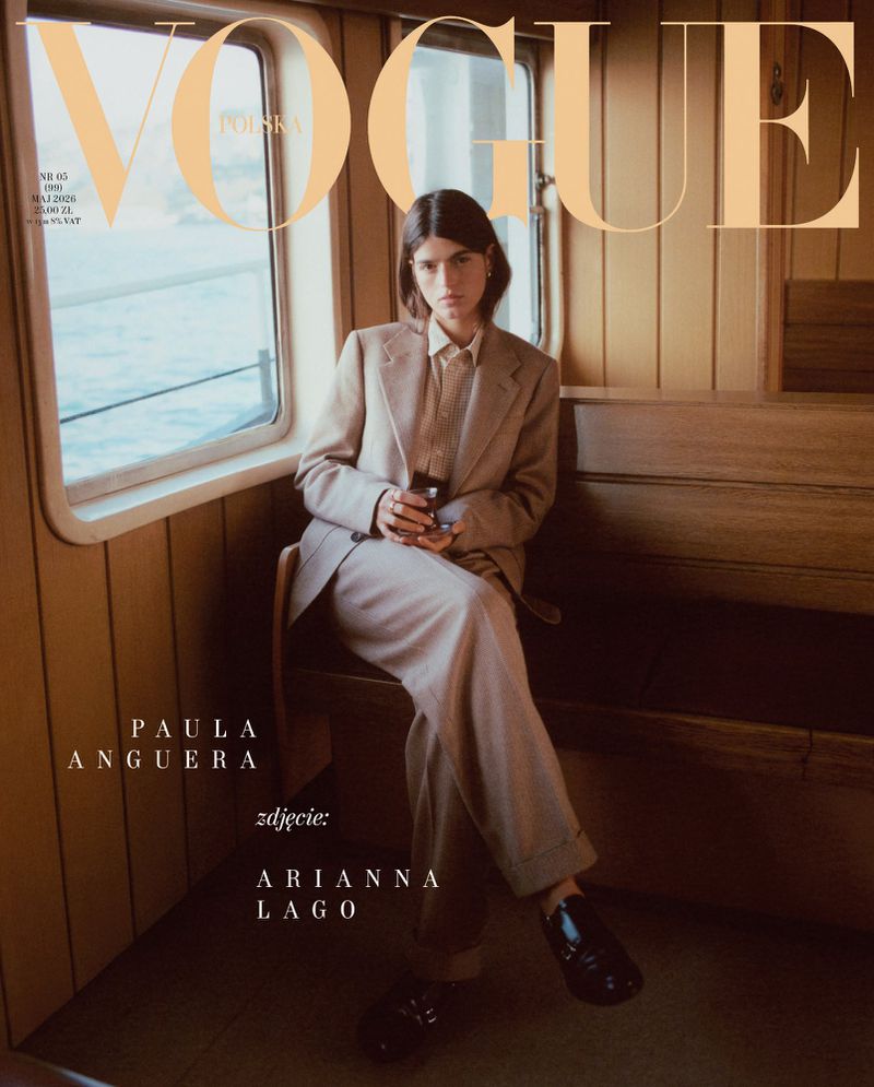 Vogue Polska cover featuring a woman in a tan suit sitting on a wooden bench by a window, holding a dark glass in her hands.