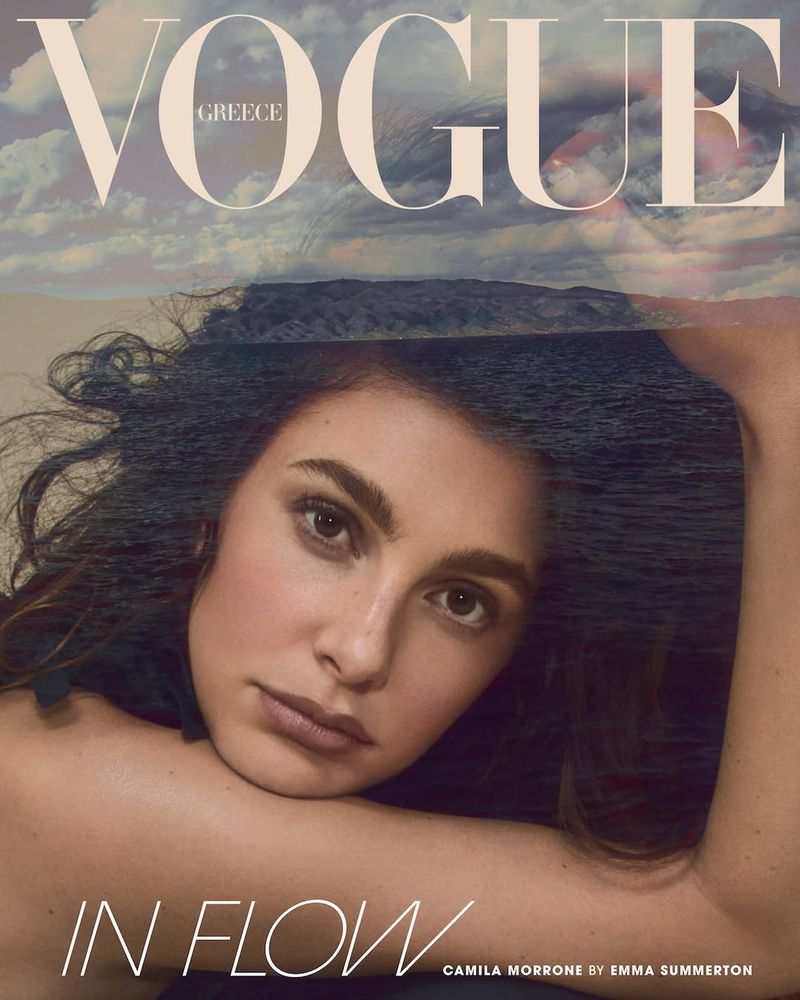Fashion magazine cover featuring Camila Morrone with a dreamy sky and ocean backdrop, styled for Vogue Greece.