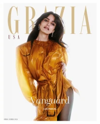 Actor Lux Pascal posing in a sheer belted amber dress against a bright white background for Grazia USA cover.