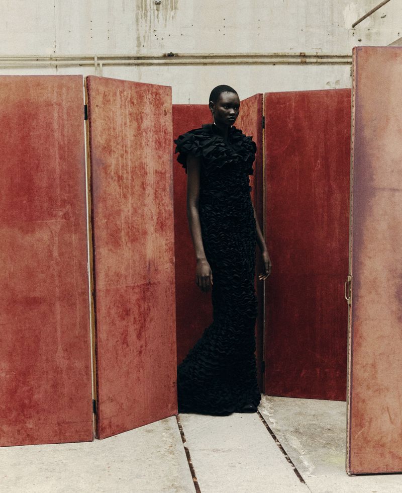 Elegant Black Woman in Couture Gown Poses with Confidence Against Studio Dividers in a Fashion Editorial Photograph