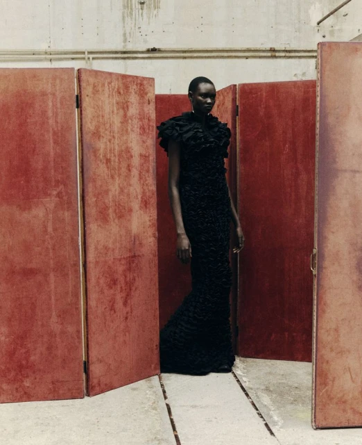 Elegant Black Woman in Couture Gown Poses with Confidence Against Studio Dividers in a Fashion Editorial Photograph
