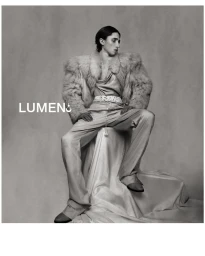 Monochrome portrait of Raphael Luce seated in a fur jacket and wide-leg trousers against a studio backdrop.