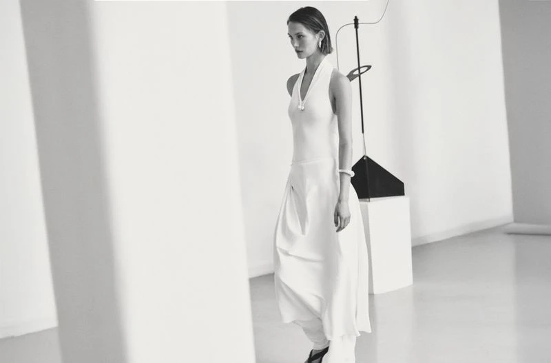 Elegant adult woman in white dress posing in a light, modern studio. Minimalist fashion photography for apparel and style.