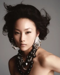 Model Wawa Li wearing statement silver fluted earrings and a chunky black beaded necklace against a seamless grey backdrop.