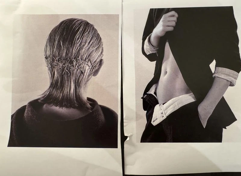 Black-and-white studio fashion shot showcases a person's back with hair secured by safety pins and another person's midsection in a blazer.