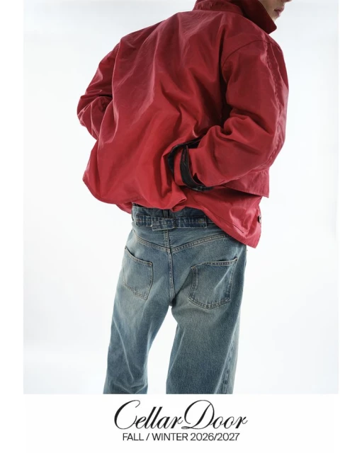 Fashion shot of a person wearing a red jacket and blue jeans against a white background in a studio. The lower back is visible.