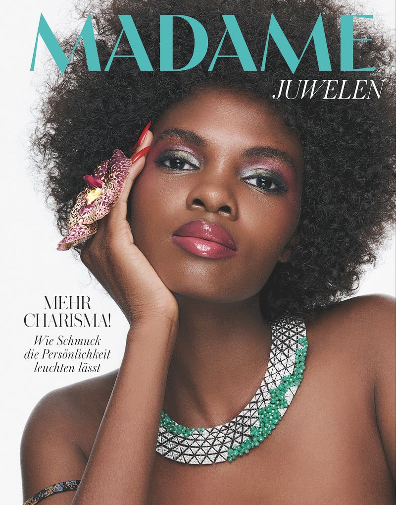 Magazine cover featuring a Black female model with an afro, wearing jewelry, and floral embellishment, against a light backdrop.