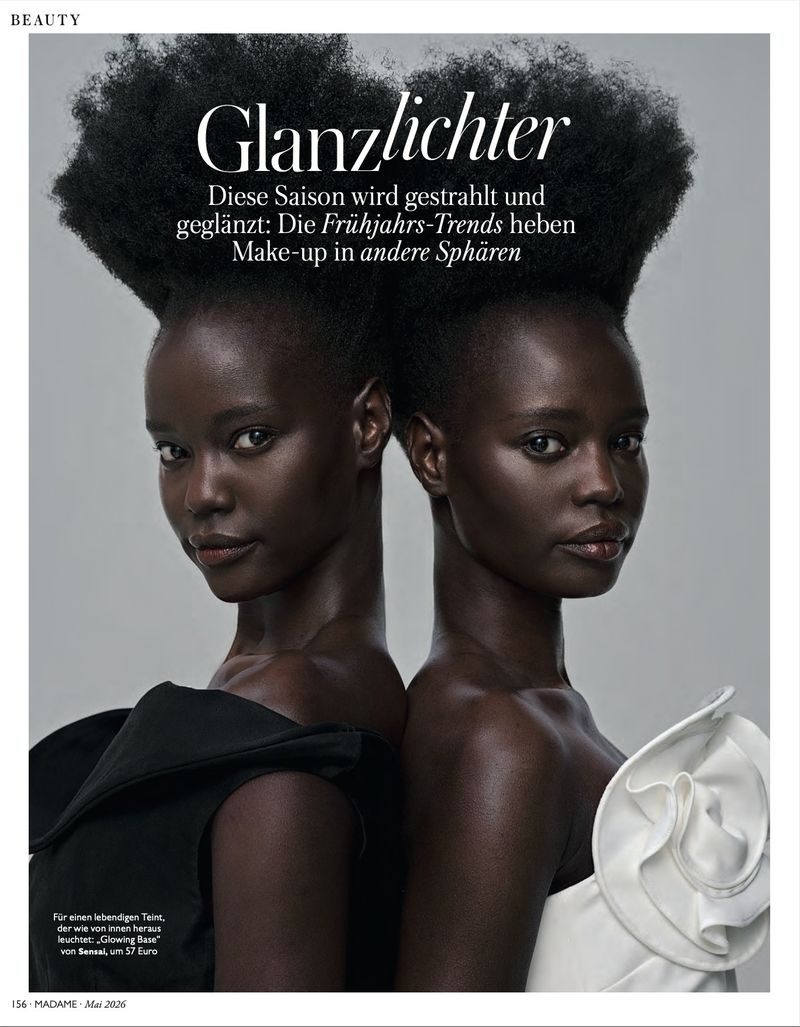 Beauty editorial featuring two African American adult females with styled natural hair, back-to-back, in a grey-toned studio environment.