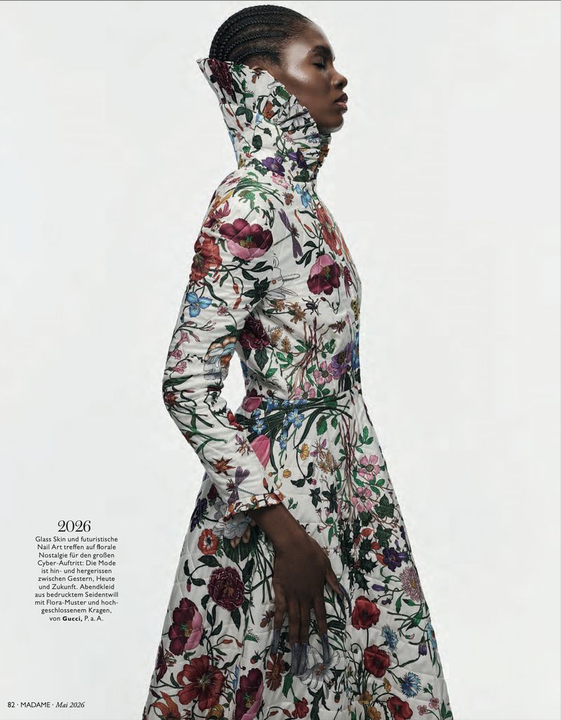 A profile fashion shot shows a Black female model wearing a white, floral-patterned, high-necked dress against a bright, minimalist background.