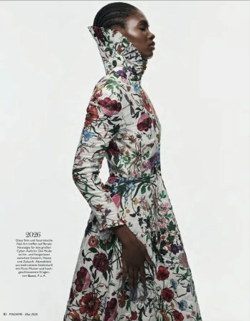 A profile fashion shot shows a Black female model wearing a white, floral-patterned, high-necked dress against a bright, minimalist background.