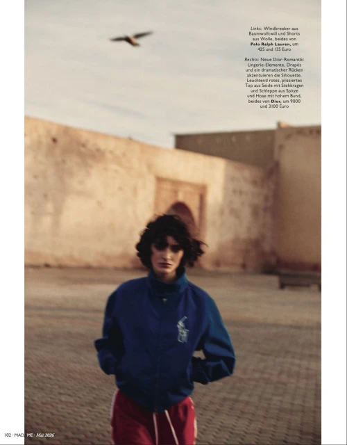 Editorial fashion shot of a young adult woman wearing a Ralph Lauren jacket and sweatpants, walking in an outdoor urban setting.