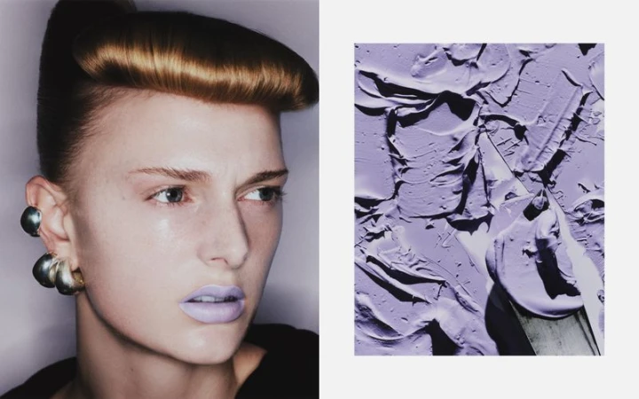 Eye-level portrait of an adult woman with styled brown hair and lavender lipstick next to a textured painting of lavender paint.