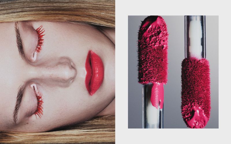 Close-up of a fair-skinned woman with red mascara and lipstick paired with lipstick product applicator wands on a neutral background.