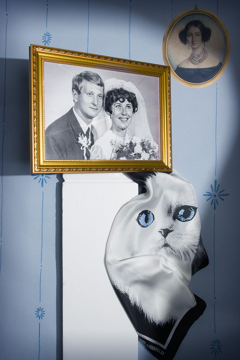 Vintage wedding photo in gold frame with portrait and Karl Lagerfeld cat scarf on floral wallpaper in blue room.
