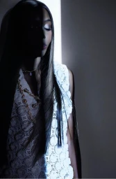 Model Naomi Campbell illuminated by a vertical slit of light wearing a white crochet top in a studio portrait by Nick Knight.