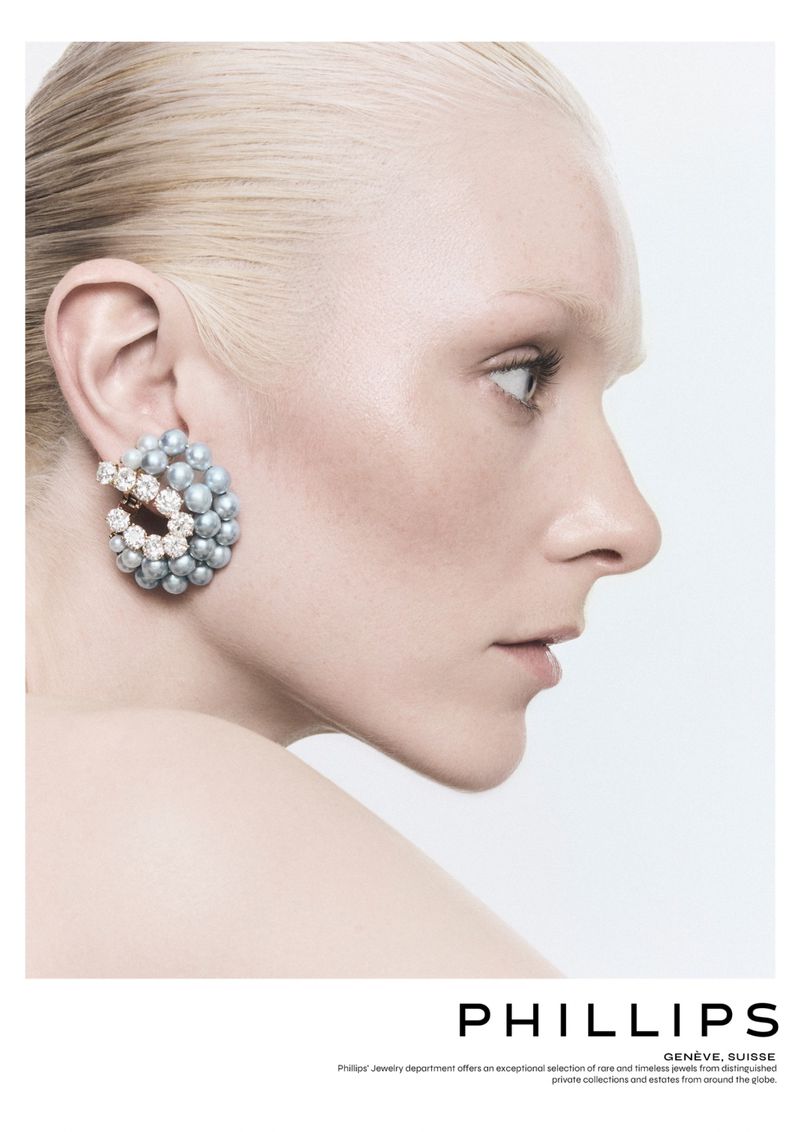 Profile shot of an adult female with light blonde hair wearing pearl and diamond earrings on a clean, white background.
