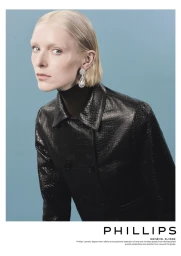 Model Jada Joyce in a black embossed leather coat and statement drop earring against a light blue studio backdrop.