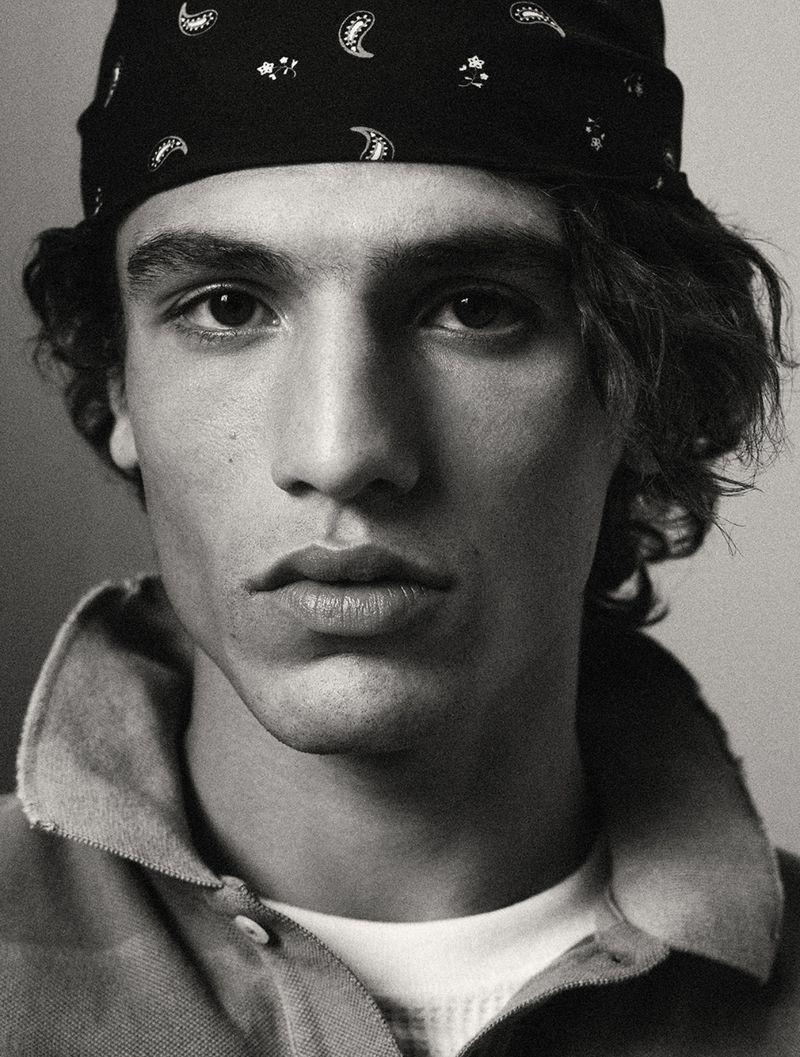 Close-up black and white portrait of a young adult male with a bandana, collared shirt, and light skin. Focus on his face.