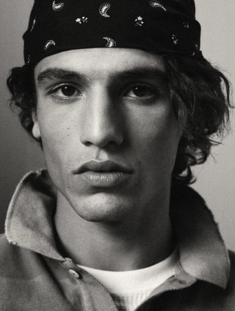 Close-up black and white portrait of a young adult male with a bandana, collared shirt, and light skin. Focus on his face.