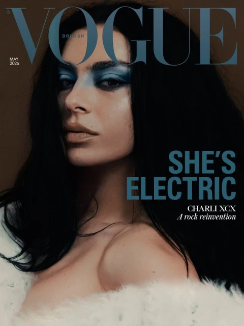 Charli XCX wearing bold blue eyeshadow and a white fluffy garment on the British Vogue magazine cover.