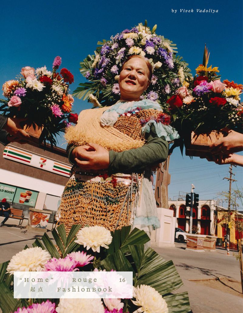 An older woman is surrounded by flower arrangements while standing outside a 7-Eleven convenience store on a sunny day.